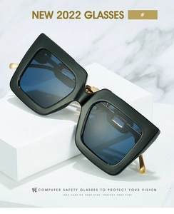 Detailed macro of black square sunglasses with gold metal temples and blue light lenses