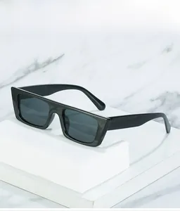Close-up of thick rectangular black sunglasses with a glossy finish on a marble stand