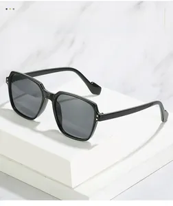 Detail of square black sunglasses on a marble platform with metallic rivet accents