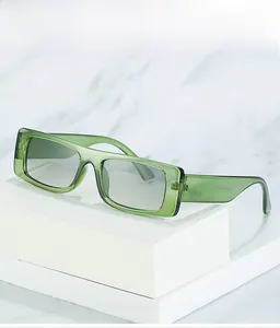 Detail of trendy green rectangular sunglasses with light grey lenses on a stone surface