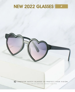 Detail of heart-shaped kids sunglasses with purple gradient lenses on a white display