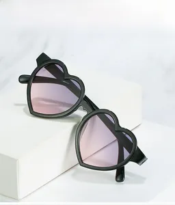 Detail of heart-shaped sunglasses with black frame and pink gradient lenses on a pedestal