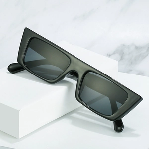 Minimalist thick rectangular sunglasses with dark lenses on white marble and stone blocks