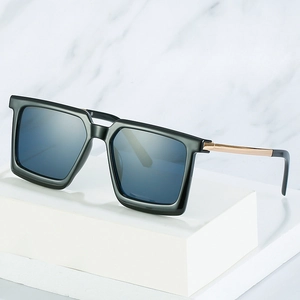 Chic black oversized square sunglasses with gold metal temples on a marble display