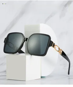 Detail of black oversized square sunglasses featuring elegant gold chain temple accents