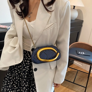 Detail of blue snake pattern mini bag with gold C-buckle and chain strap on a model