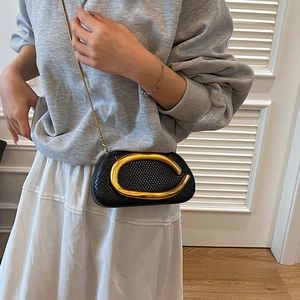 Detail of snake-embossed leather texture with a large golden oval metal clasp on the bag