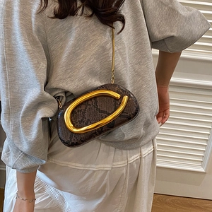 Detail of snake pattern leather crossbody bag with large gold metal ring and chain strap