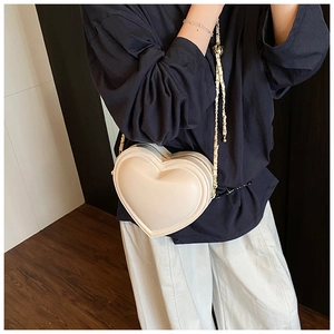 Close-up of heart-shaped handbag featuring premium cream leather and gold chain strap