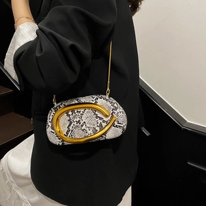 Detail of snake skin pattern handbag with gold crescent handle and elegant metal chain
