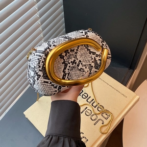 Detail of snake pattern evening bag with iconic large gold C-shaped metal handle