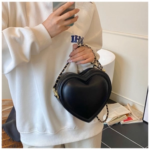 Detail of black heart-shaped bag with gold chain strap and elegant quilted leather texture