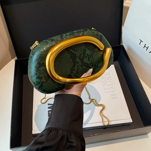 Detail of green snake pattern clutch featuring large gold C-shaped metal handle and chain