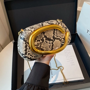Close-up of snake skin texture evening bag with golden C-handle and fine chain
