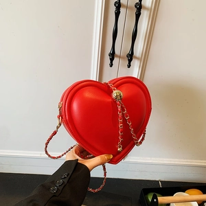 Red heart-shaped leather crossbody bag with elegant gold chain strap and zipper