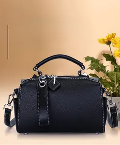 Détail du sac à main en cuir grainé noir avec coutures blanches et finitions argentées