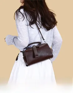 Gros plan d'un sac Boston marron à motif litchi avec détails argentés et coutures rétro