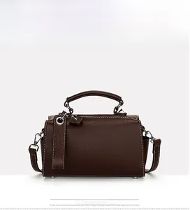 Détail du sac à main en cuir marron foncé avec surpiqûres blanches et finitions argentées