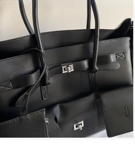 Detail of black leather tote bag featuring glossy texture and silver twist-lock hardware