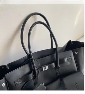Detail view of the durable double leather handles and silver metal turn-lock on the black tote