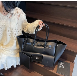 Detail of a black large tote bag with silver twist lock and extra pouch on wooden steps