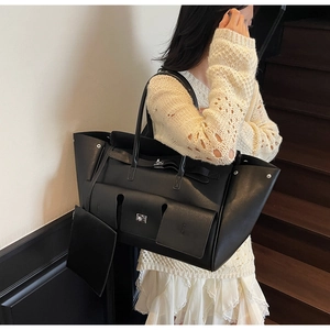 Detail of black leather tote bag with functional front pockets and a mini pouch charm