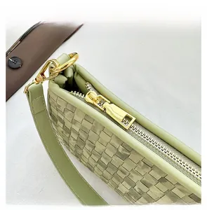 Détail du sac tressé vert clair avec fermeture éclair dorée et crochets de sangle