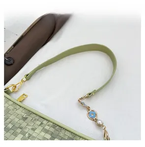 Détail d'un sac en cuir tressé vert avec fermeture éclair dorée et pendentif floral