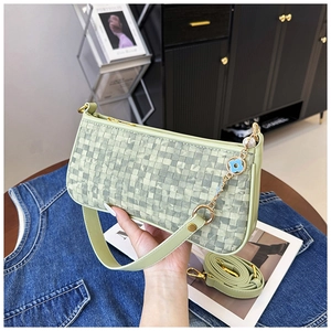 Détail du sac carré tressé vert clair avec chaîne florale bleue et bandoulière