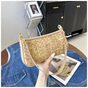 Détail d'un sac à bandoulière tissé beige avec chaîne en métal et breloque fleur rose
