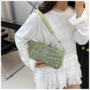 Détail de texture tressée vert clair sur sac avec bandoulière en perles et chaîne