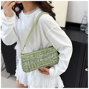 Détail de la texture tissée vert clair sur sac bandoulière avec boucle dorée élégante