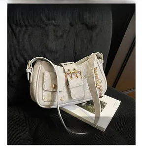 Detail of grey crossbody bag featuring silver star rivets and metallic chain accents