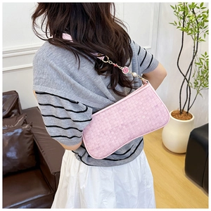 Détail du sac bandoulière rose tressé avec chaîne en métal ornée de petites fleurs