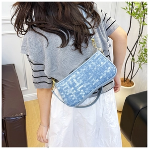 Détail d'un sac bandoulière tissé bleu clair avec chaîne dorée et bandoulière en cuir