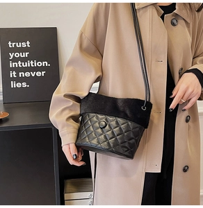 Close-up of plush stitching and quilted leather on a bucket bag worn with a trench coat