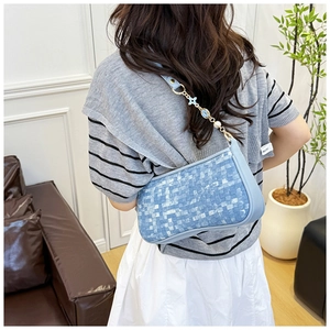 Sac à bandoulière tissé bleu avec chaîne et décor de fleurs porté par un mannequin