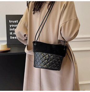 Detail of black quilted leather bucket bag with plush faux fur trim and shoulder strap