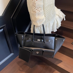 Black leather tote bag with silver buckle and coin purse worn in a lifestyle setting