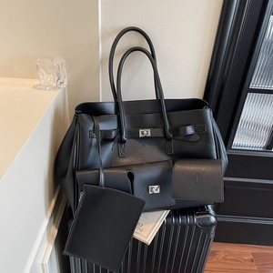 Large black tote bag set with buckle closure and matching mini pouches on a suitcase