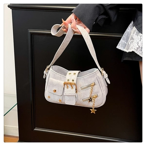 Close-up of denim shoulder bag with golden star pendant and textured flap pocket