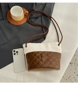 Close-up of quilted leather bucket bag with plush trim next to a smartphone
