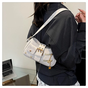 Close-up of a white textured leather baguette bag with gold buckle and star charm detail