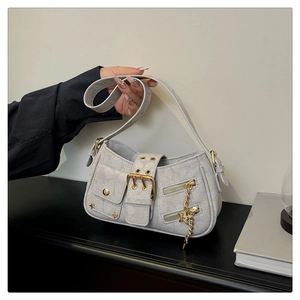 Detail of light blue denim underarm bag with gold buckles and star metal charms