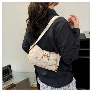 Detail of off-white shoulder bag with metal belt buckle and star chain charm on a model