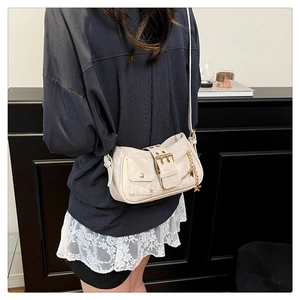 Detail of a chic cream-colored studded underarm bag featuring a gold star charm accessory