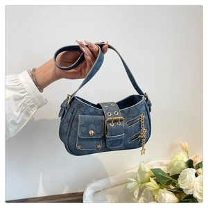 Close-up of denim shoulder bag featuring metal zippers and a gold star charm accessory