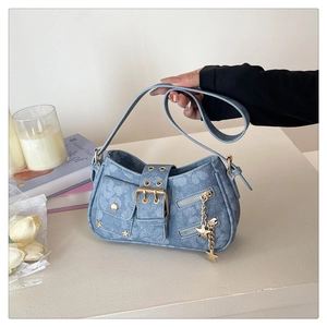 Detail of Y2K denim armpit bag with gold star chain and moto-style buckle texture