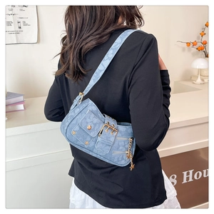 Close-up of light blue denim shoulder bag featuring gold star rivets and metal buckle