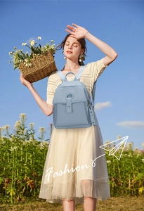 Outdoor lifestyle shot of a light blue lychee pattern backpack worn with a beige dress